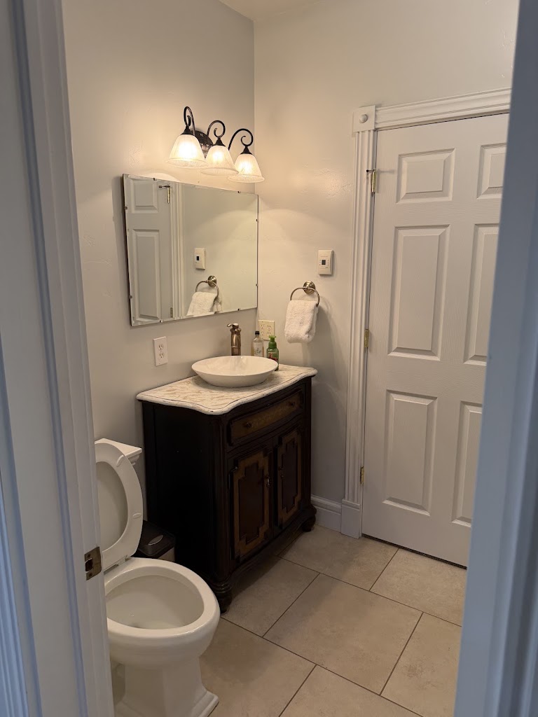 Bathroom with a vessel sink, dark wood vanity, wall mirror, and tile floor