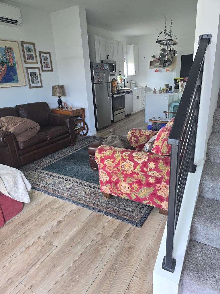 Furnished living room with a sofa, floral armchair, area rug, and adjoining kitchen