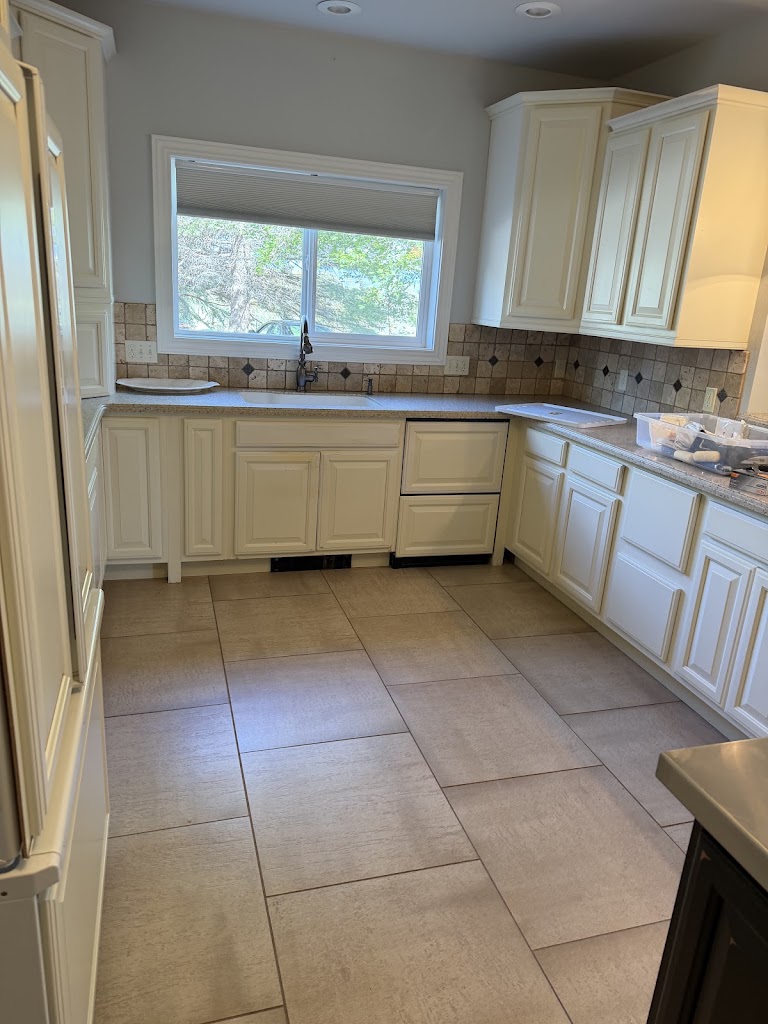 Kitchen with cream cabinets, a window above the sink, tile flooring, and supplies on the counter